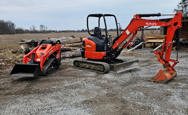 A compact tracked loader and mini excavator on a gravel work site