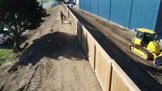 Drone view along the wood fence beside a blue-sided building
