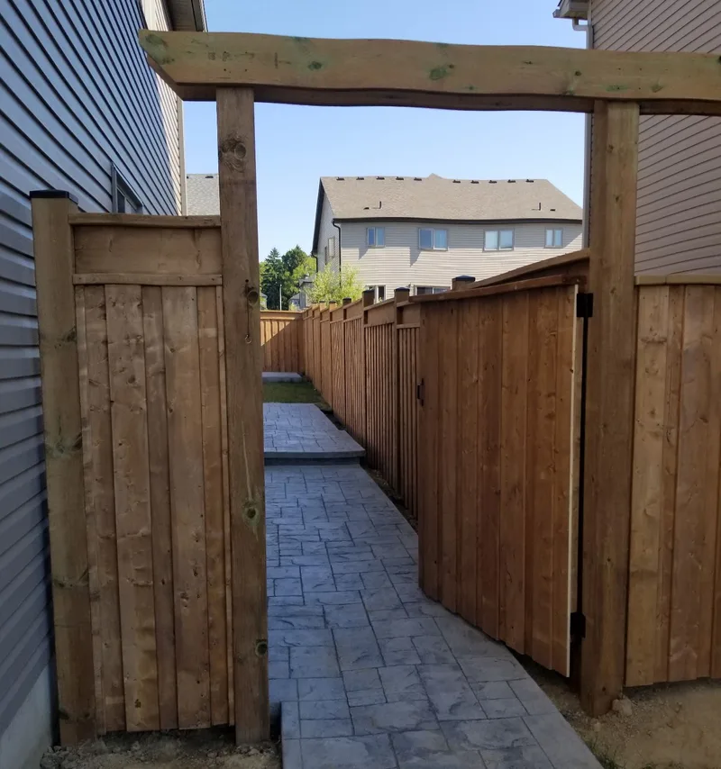 Wood gate and overhead frame at the entrance to a paved side path