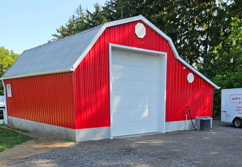Red barn with vertical siding, white trim and a white overhead door