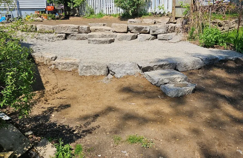 Tiered armour-stone retaining walls and stone steps in a Simcoe backyard